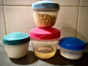 Popping corn, salt, sugar and oil in small containers.