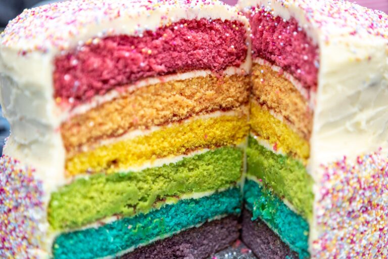 A close up of the inside of a birthday cake, with lots of coloured layers.